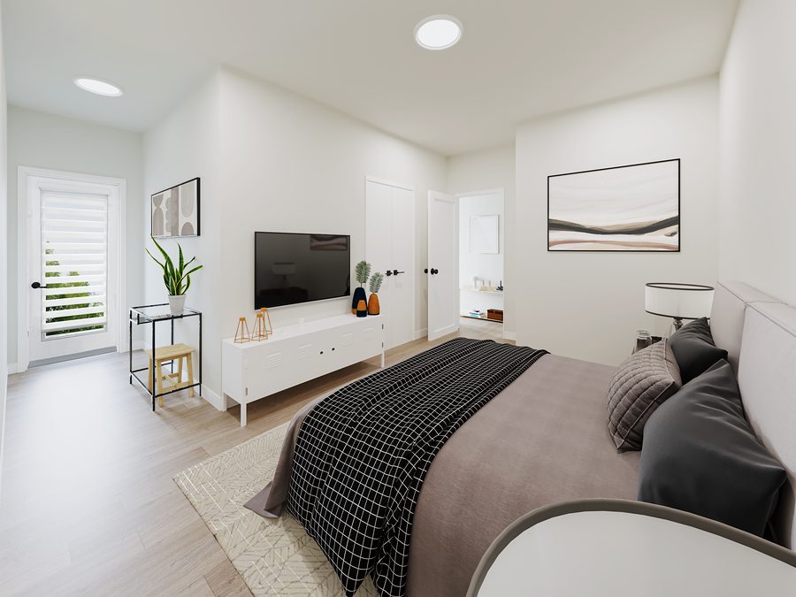 Second bedroom in a 1811 John Brebeuf rental townhome with a white media unit and bright natural light